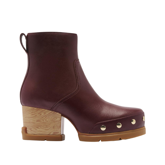 A side-profile view of a dark burgundy leather ankle boot with a chunky wooden block heel, a tan sole, and gold-tone metal studs on the toe, set against a plain white background.