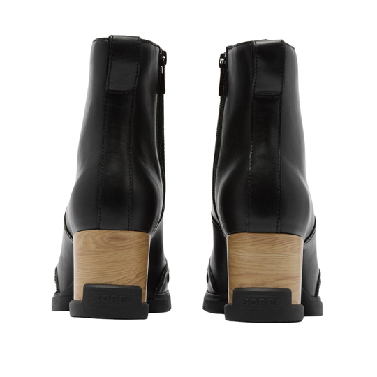 A pair of black leather ankle boots with a chunky wooden block heel, shown from the back on a white background. The brand name 'sorel' is embossed on the heel.