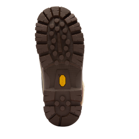 A top-down view of a brown rugged shoe sole with deep lugs and a small yellow Vibram logo in the center, isolated on a white background.