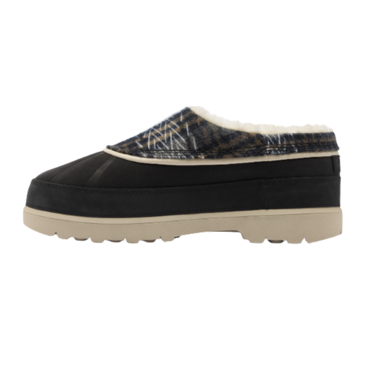 A single slip-on mule shoe shown in profile against a plain white background. The shoe has a black suede-like upper, a patterned fabric inlay in dark blue and beige tones, a cream-colored shearling lining at the opening, and a thick beige sole.