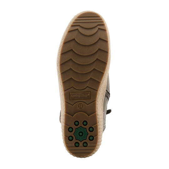 The outsole of a Spring Step boot, showing a tan rubber tread with a green circular traction pattern and the brand name 'Spring Step' embossed on the heel, set against a plain white background.