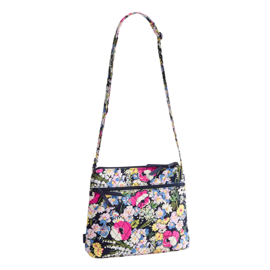 A floral crossbody handbag with a long shoulder strap, featuring a multicolor pattern of pink, yellow, blue, and white flowers on a dark background, shown against a plain white background.
