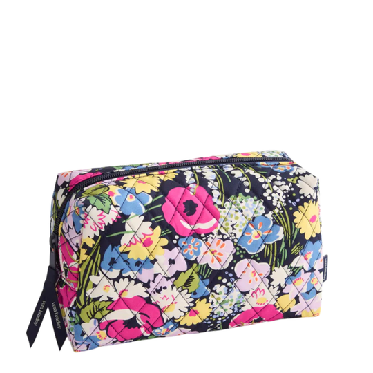A rectangular quilted cosmetic pouch with a vibrant multicolor floral print on a dark navy background, featuring a top zipper and a black brand tag on the left side.