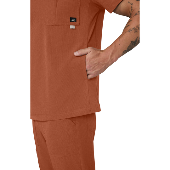Person wearing a brown scrub set with a visible brand logo on a white background