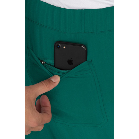 Close-up of a teal green scrub or uniform pocket with a black smartphone tucked inside, and a hand pulling the pocket open.