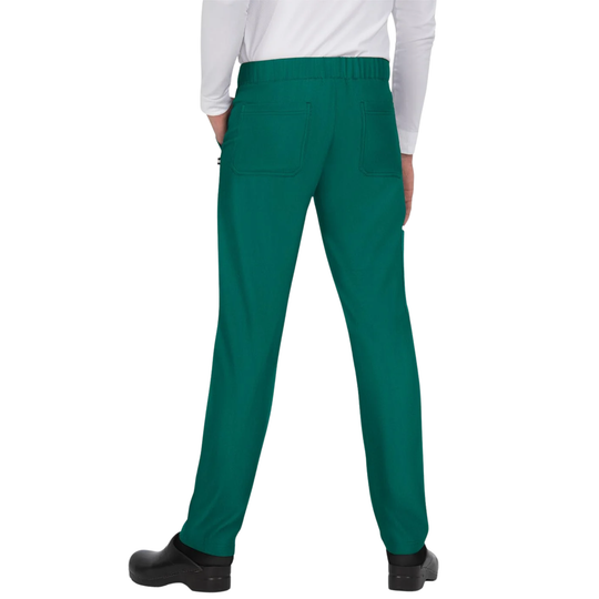 A person shown from the back wearing bright green scrub pants with a white long-sleeve top and black clogs, against a plain white studio background.