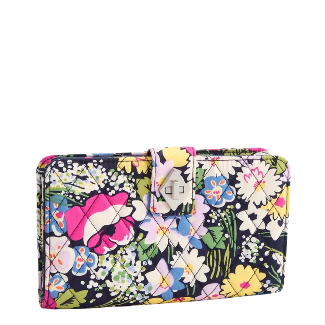A rectangular clutch wallet with a vibrant multicolor floral print on a dark navy background, featuring a silver-tone metal turn-lock clasp closure.