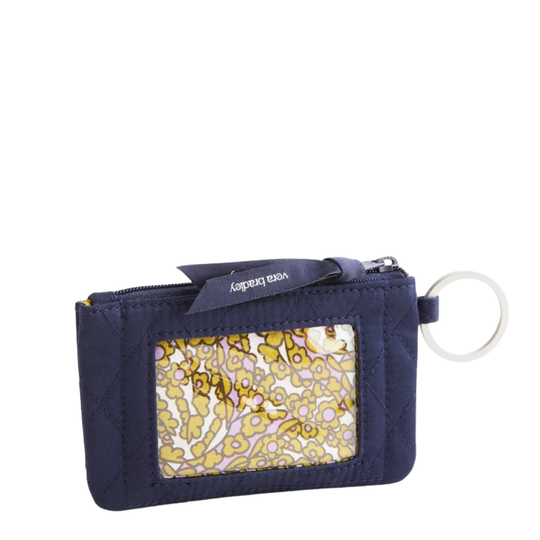 A navy blue quilted card holder wallet with a yellow and white patterned ID window, a navy blue zipper pull tab with the brand name 'vera bradley', and a white key ring.