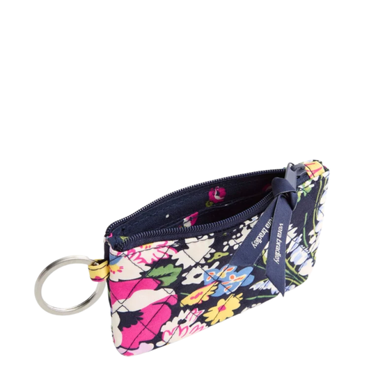 A small zippered pouch with a colorful floral print on a dark navy background, featuring a silver key ring and a navy ribbon tag with the brand name 'Kerry James'.