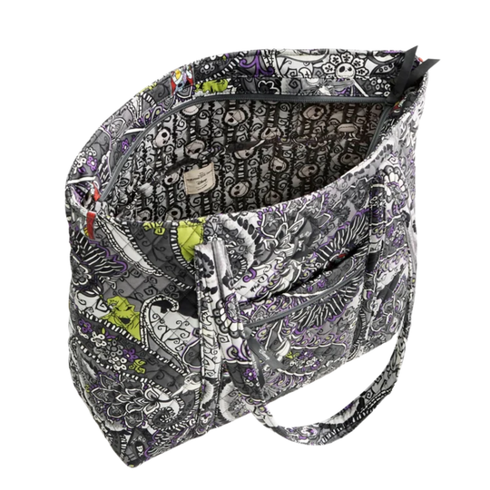 A tote bag with a black, white, and gray skull-and-floral pattern, featuring a bright lime green accent patch on the front pocket and a matching patterned interior lining.