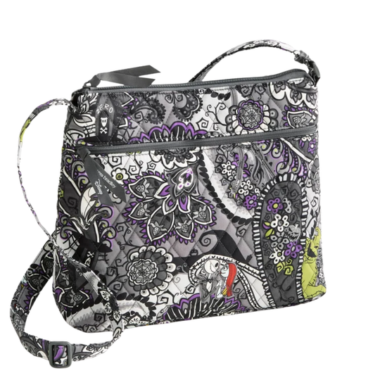 A crossbody bag featuring a detailed black, white, and gray floral and paisley pattern with purple and lime green accents, shown on a plain white background.