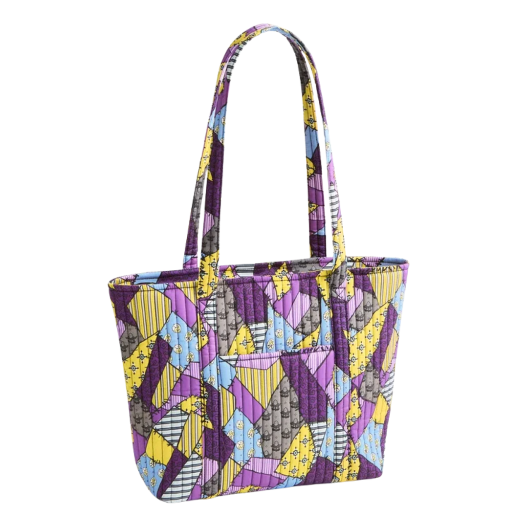 A quilted fabric tote bag featuring a colorful geometric patchwork pattern in purple, yellow, blue, gray, and black, set against a plain white background.