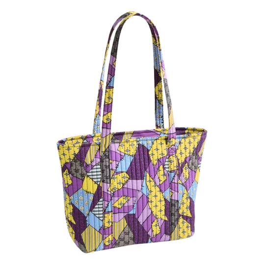 A quilted tote bag featuring a vibrant geometric patchwork pattern in purple, yellow, blue, and gray, set against a plain white background.