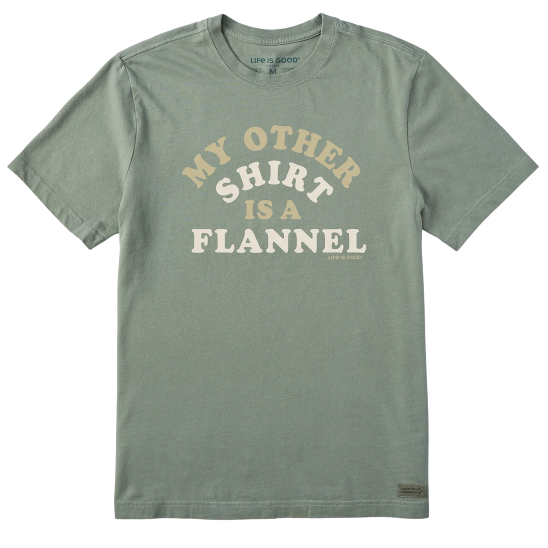 A sage green crewneck t-shirt with a graphic text print reading 'MY OTHER SHIRT IS A FLANNEL' in cream and white lettering, displayed flat against a white background.