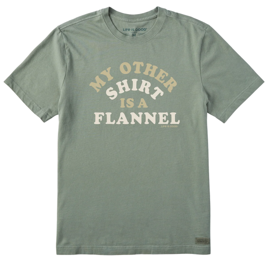 A sage green crewneck t-shirt with a graphic text print reading 'MY OTHER SHIRT IS A FLANNEL' in cream and white lettering, displayed flat against a white background.