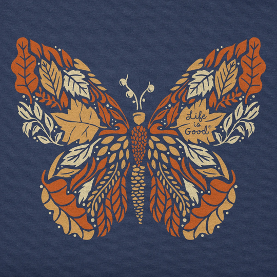 A close-up of a navy blue fabric featuring a large butterfly graphic made from orange, tan, and cream leaves, with the phrase 'Life is Good' printed on one wing.