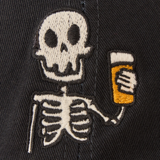 Close-up of a black embroidered cap featuring a white skeleton holding a yellow-orange beer mug.