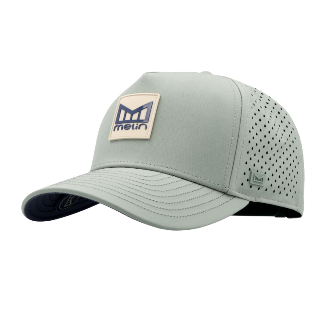 A light sage green performance cap with a curved brim, perforated back panels, and a beige logo patch on the front.
