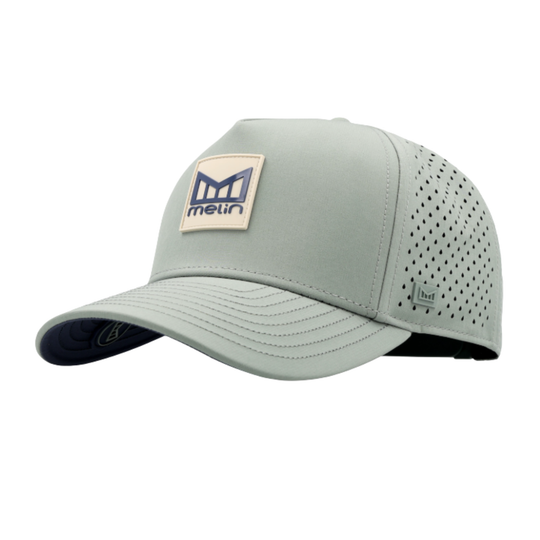 A light sage green performance cap with a curved brim, perforated back panels, and a beige logo patch on the front.