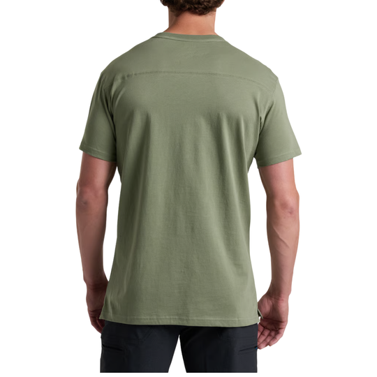 A man viewed from the back wearing a short-sleeve crewneck t-shirt in sage green, paired with dark pants, against a plain white background.