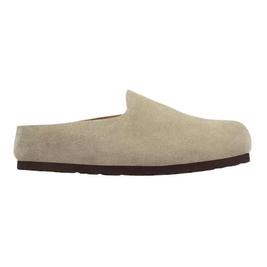 A single slip-on clog shoe in light beige suede with a dark brown sole, shown from a side profile view on a plain white background.