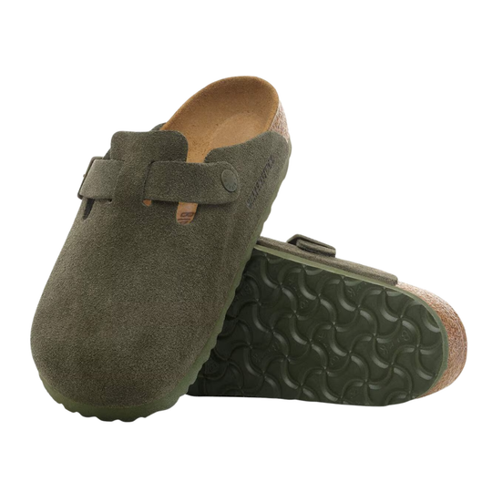 A pair of Birkenstock Boston clogs in olive green suede, with one clog standing upright to show the side profile and strap, and the other lying on its side to display the textured cork footbed and sole.