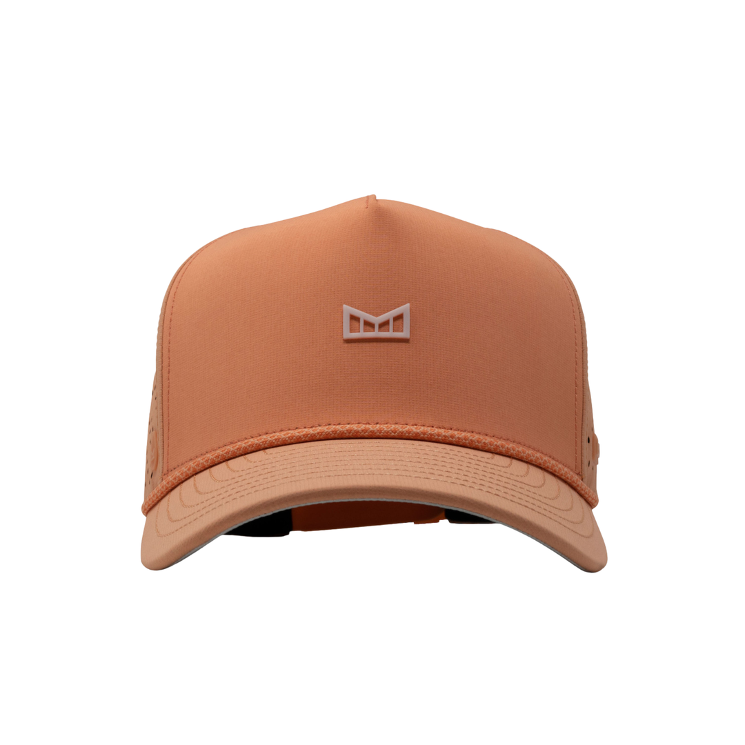 A structured trucker-style cap in a muted peach-orange color, featuring a matching embroidered geometric logo on the front panel and a curved brim, set against a plain white background.