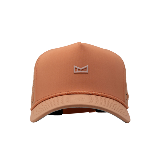 A structured trucker-style cap in a muted peach-orange color, featuring a matching embroidered geometric logo on the front panel and a curved brim, set against a plain white background.