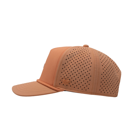 A structured baseball cap in a warm tan or peachy-brown color, featuring perforated panels on the front and side, a matching curved brim, and a small embossed logo on the side.