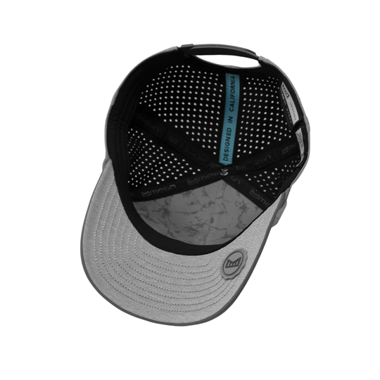 A structured baseball cap shown from a top-down angle, featuring a black perforated mesh back, a light gray curved brim with a subtle gray marble pattern, and a small circular logo on the front of the brim.