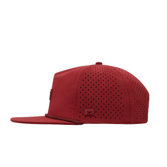 A red flat-brim cap with perforated panels on the front and side, featuring a small square logo patch on the side and a braided trim detail along the edge of the brim, shown against a plain white background.