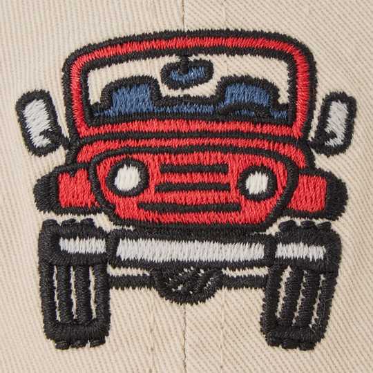 Close-up of an embroidered red vintage car patch on a beige fabric surface, with black, white, and blue thread details.