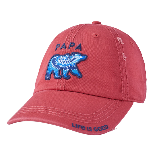 A washed red baseball cap featuring an embroidered blue polar bear with a tie-dye pattern and the word 'PAPA' above it, with 'LIFE IS GOOD' embroidered on the brim.