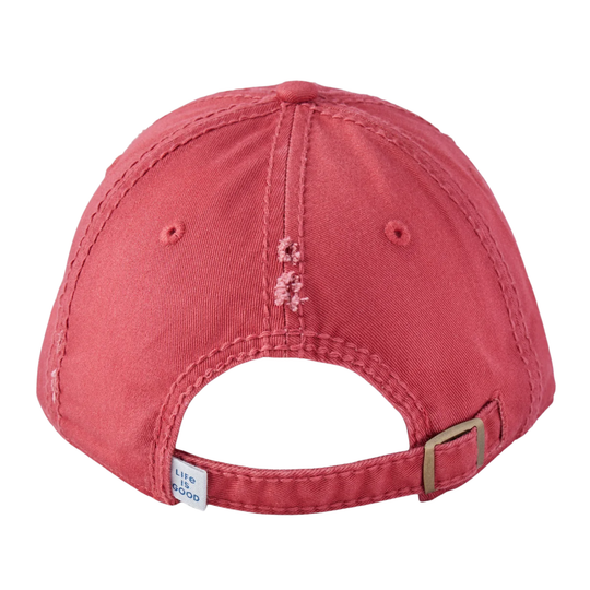 A close-up back view of a distressed coral pink baseball cap with a metal buckle and a small white brand tag that reads 'LIFE is good'.