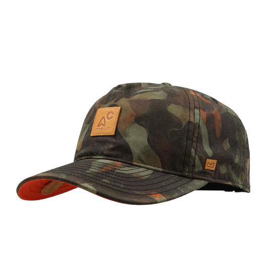 A baseball cap in a green, brown, and black camouflage pattern, featuring a tan leather patch on the front with the 'AC' logo and 'melin' underneath.The underside of the brim is orange.