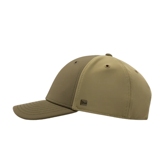 A structured baseball cap in a muted khaki-tan color, shown from a side profile view against a solid white background. A small black brand patch is visible on the side panel.