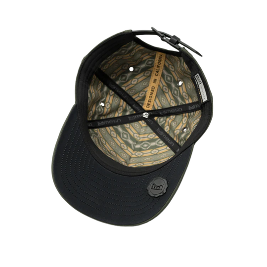 The underside of a black baseball cap, showing the interior lining with a tan and green pattern, adjustable strap, and a circular black logo patch on the brim.