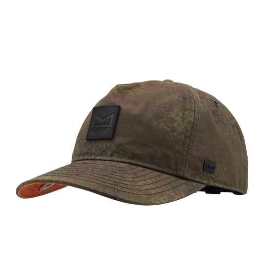 A distressed camouflage baseball cap in shades of brown and green, featuring a black rectangular patch on the front with the 'Melin Design' logo and a small black logo patch on the side, set against a plain white background.
