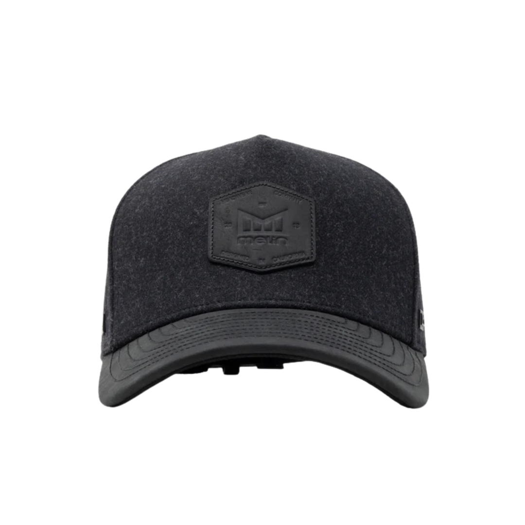 A black textured baseball cap with a tonal black hexagonal patch on the front featuring the brand name 'Melin'.