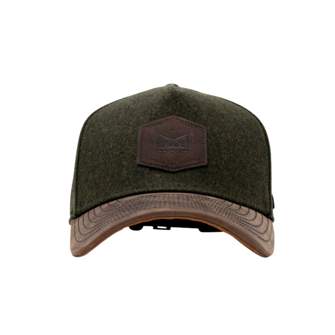 An olive green felt baseball cap with a brown leather patch on the front featuring an embossed 'M' logo, and a brown leather visor trim, shown against a plain white background.