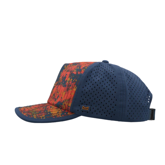 A navy blue baseball cap with a perforated front and side panels, and a curved brim featuring a vibrant orange, red, and yellow abstract pattern. A small orange and black logo patch is visible on the side.