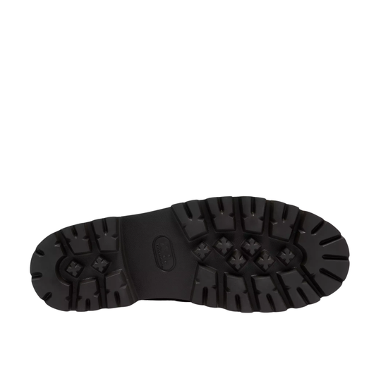A close-up, top-down view of a black rubber boot sole with deep lugs and textured tread patterns, set against a plain white background.