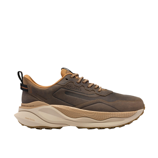 A brown and tan outdoor sneaker with a chunky beige midsole and a small orange accent on the heel pull tab, shown from a side profile on a white background.