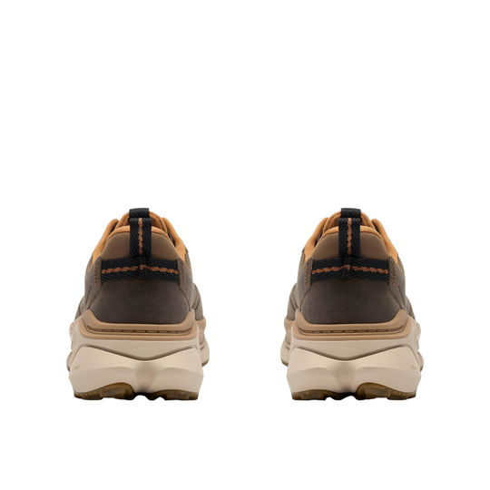 A pair of low-top lace-up shoes shown from the back, featuring a dark brown suede upper, tan leather trim, and a chunky off-white midsole with a gum outsole.
