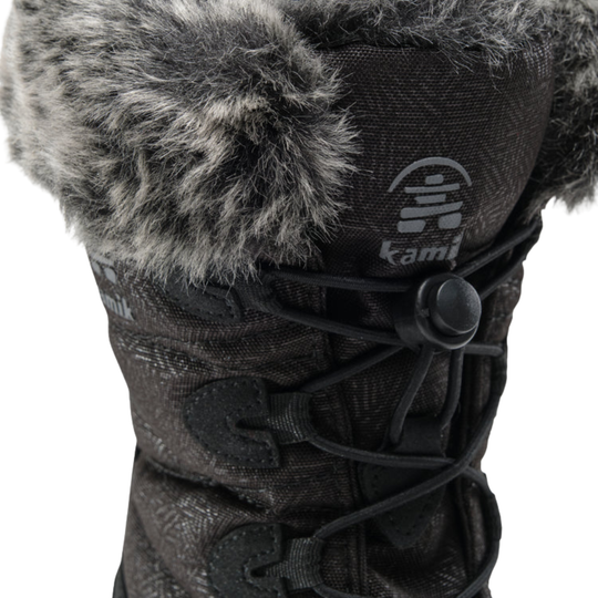 Close-up of a black winter boot with gray faux-fur trim around the collar and a black lace-up front, shown on a white background. The kamik logo is visible on the tongue.