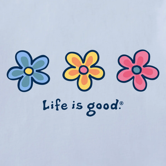 A close-up of a light blue garment featuring a graphic of three retro-style flowers in blue, yellow, and pink, with the text 'Life is good.' printed below in dark blue.