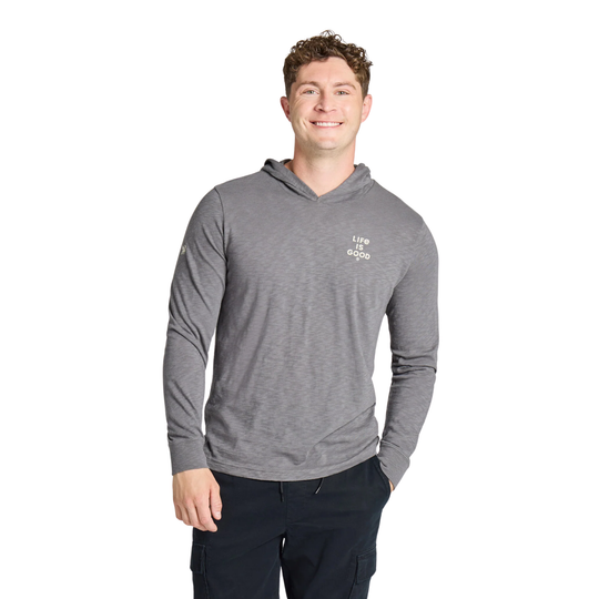 A man wearing a heather gray long-sleeve hooded shirt with a small white 'life is good' logo on the left chest, paired with dark pants, against a plain white background.