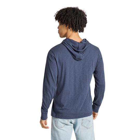 A man with curly black hair is shown from the back wearing a heathered navy blue long-sleeve hoodie and light wash jeans against a solid white background.