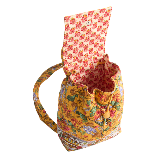 A small fabric bucket bag with a multicolor floral and bird print, featuring a yellow base, a matching shoulder strap, and an open top with a floral-patterned lining.