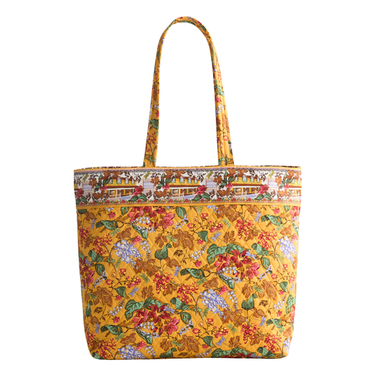 A yellow tote bag with a dense floral and botanical print, featuring a decorative border pattern along the top and matching shoulder straps, set against a plain white background.